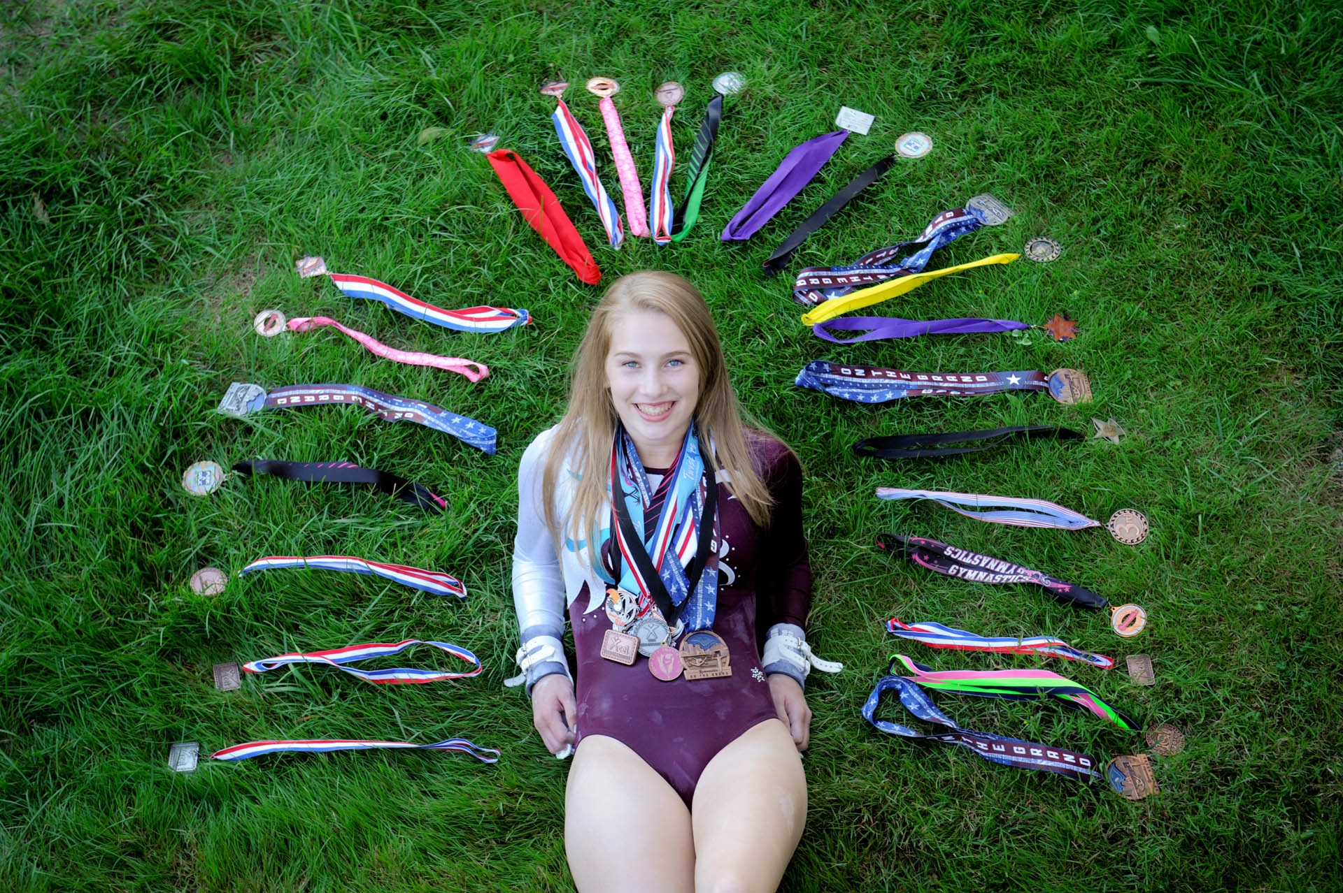 Troy , Michigan senior photographer shows a high school gymnast senior poses with many of her many ribbons for her senior pictures in Troy, Michigan.